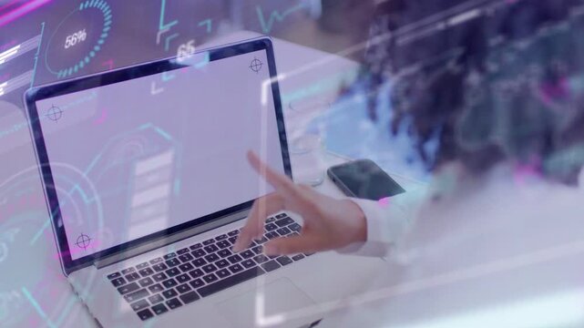 Woman tapping laptop trackpad at desk, updating HUD values for tech demo while phone resting nearby