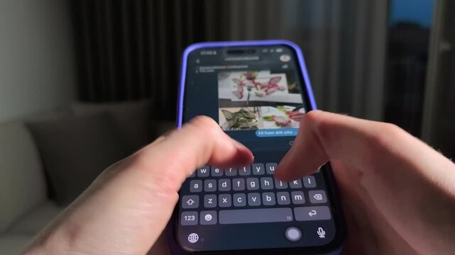 Hands type a message on a smartphone in a purple case. The mobile chat screen stays in close up while the thumbs move across the keyboard. Online messaging, texting, and social communication