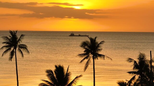 Red orange Sunset sky over the ship running on sea surface and tropical beach in Santa Fe, Tablas, Romblon. Philippines.