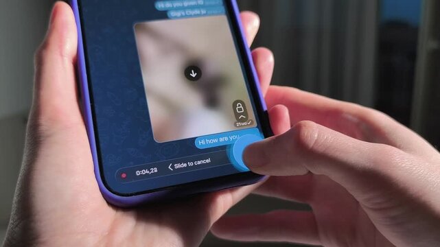 Hand holds smartphone with chat screen and voice message. Thumb taps a mobile interface in close up. Messaging app communication concept for social media and device mockup..