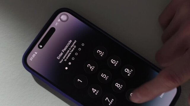 Hand enters passcode on smartphone lock screen. Close up view of a mobile keypad with Face ID notice and moving finger. Security, access, and device unlocking concept..