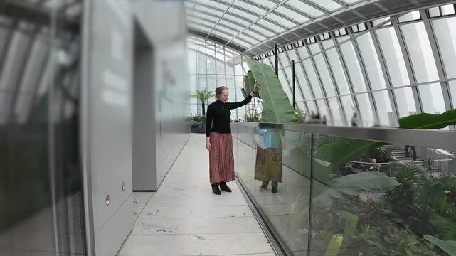 Woman touching large plant leaf in rooftop botanic garden experience