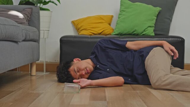 Young man experience vertigo slips and falls flat onto living room floor