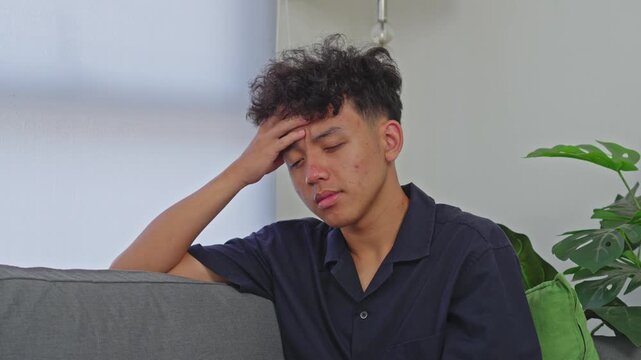 Sad young male feeling unwell and dizzy while head on hand while experiencing burnout