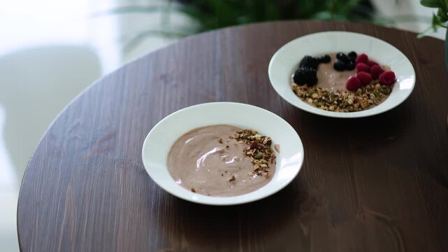 Close up hand mixing Greek yogurt whey protein smoothie bowl with granola and seeds healthy breakfast video 4K