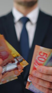 Formally dressed man is counting Canadian Dollar bills, close-up.