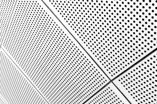 Perforated metal panels curving on architectural ceiling