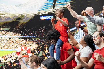 Fototapeta premium Proud dad celebrates with young fan son at football stadium for soccer match. Parent child connection and multigenerational family support through cheering fans and joyful childhood experience.