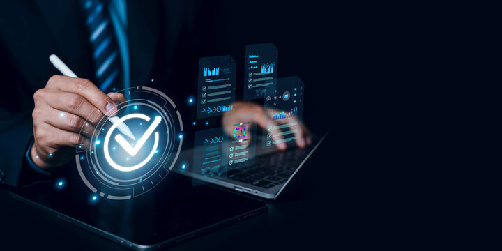 Businessman using stylus pen on tablet with digital check mark and data charts interface, quality assurance, compliance control and online financial auditing concept on dark background.