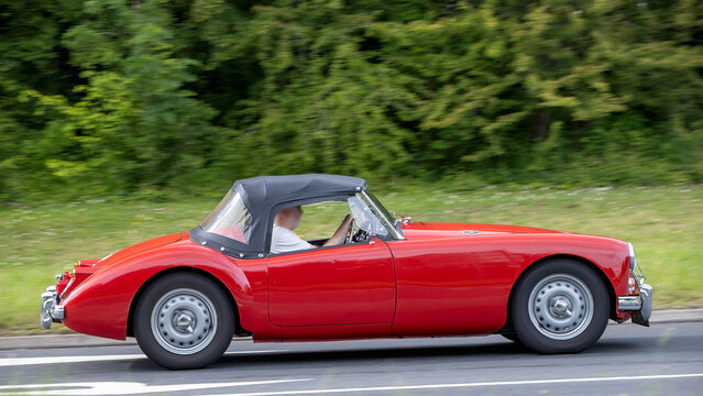 Milton Keynes,Bucks,UK - May 21st 2026:  1959 red MGA Twin Cam Roadster classic car driving on a British road