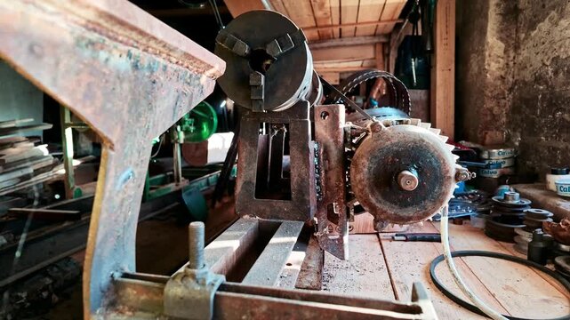 Rusty, old lathe machine in an abandoned and cluttered workshop or garage