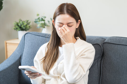 Presbyopia, Hyperopia middle aged asian woman hand rubbing her eye with vision blurred ,girl trying to read text message from smart mobile phone screen, eye disease of old, eyesight farsightedness.