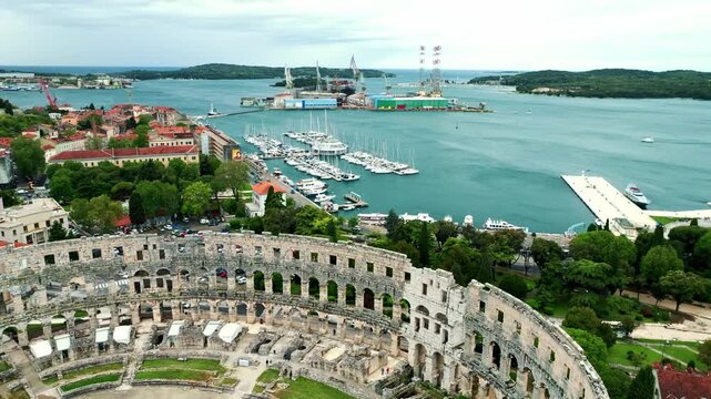 Cinematic aerial drone footage of Pula featuring historic architecture, Adriatic coastline, marina, and Mediterranean atmosphere. Scenic coastal views and ancient Roman heritage .