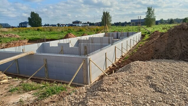 Concrete foundation of house under construction on building site. ICF block walls, rebar reinfocement, groundworks in rural field.
