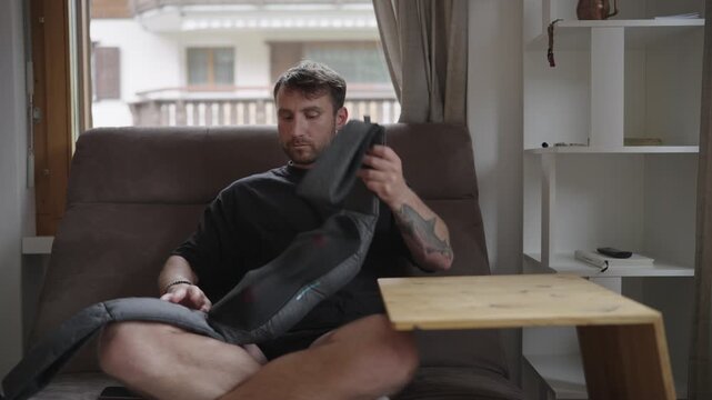 Young man relaxing on the couch while using an electric shiatsu back and neck massager