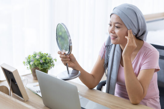 asian women disease mammary cancer patient lady looking at mirror with pink ribbon wearing headscarf After treatment to chemotherapy with working business at laptop in office at home,medicine concept