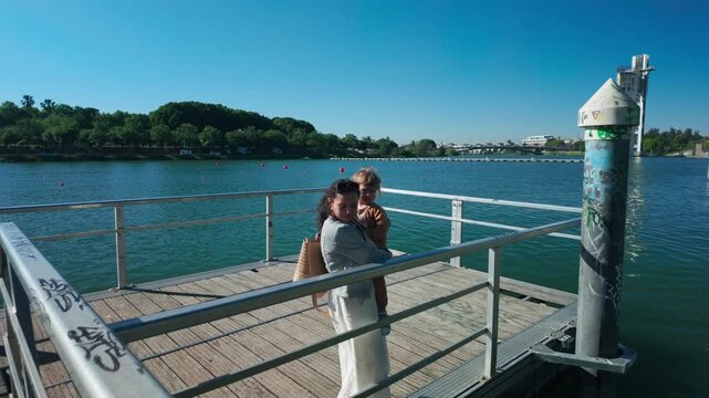 Mother and Child Enjoy a Serene Sunny Day on a Pier Overlooking the Tranquil Waters in Sevilla, Spain