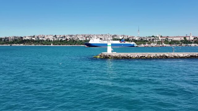 A beautiful view of the small white lighthouse on the rocky breakwater of Kadikoy district in Istanbul, Turkey.