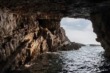 Fototapeten Sommer Dramatic view from the inside of a rocky cave, overlooking the vast sea under a vibrant sky. The scene evokes a sense of nature raw, untouched beauty and tranquility. Blue cave, Montenegro  © evannovostro