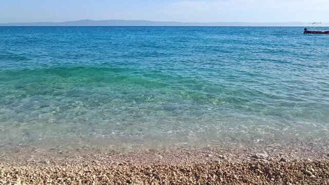 Transparent Sea Waves Washing White Pebble Beach Shoreline, Close Up View of Clear Ocean Water and Smooth Stones With Gentle Surf in Sunny Weather, Relaxing Coastal Nature Background With Soft Sea