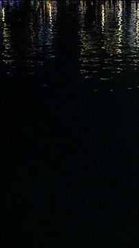 Colorful light reflections on water ripples at night, abstract neon background with copy space.
Abstract colorful reflections on rippling water at night. Vertical, mobile format.
