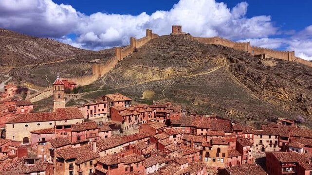 Panoramic view of Albarracin, medieval village with ancient fortified walls climbing rugged hills above terracotta rooftops, Teruel province, Aragon, Spain