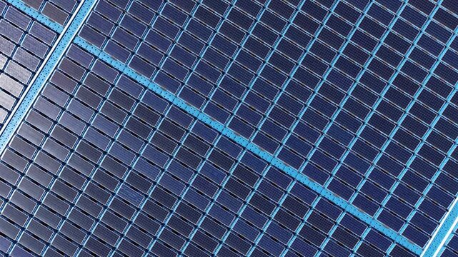Top-down close-up view of floating solar panels arranged in diagonal rows, showing blue photovoltaic cells with structural frame dividers at a renewable energy installation