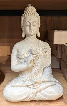 Escultura de piedra de Buda sentado con las piernas cruzadas en la postura de loto y gestos mudra en las manos en estante de comercio