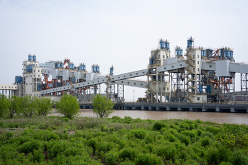 Fototapeta premium Large industrial port loading and unloading equipment facilities by the river