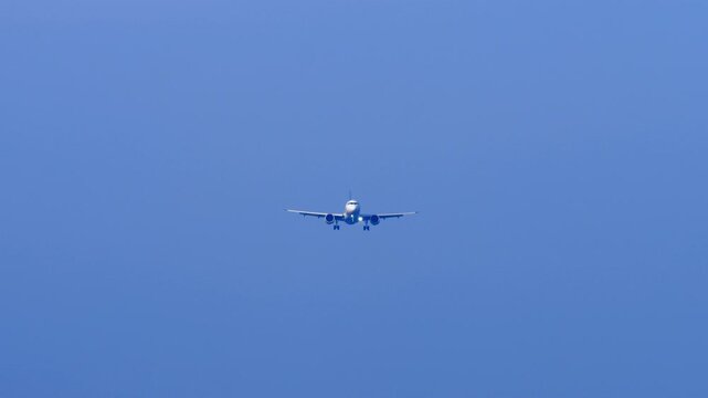 Commercial passenger jet airliner flying low in the cloudy sky on final landing approach toward Phuket International Airport.