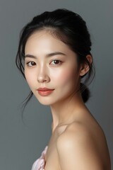 Naklejka premium Portrait of a young woman with natural makeup and flawless skin, studio shot on a grey background, elegant beauty and skincare concept.