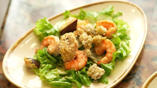 Fresh Caesar salad with grilled shrimps on a beige plate