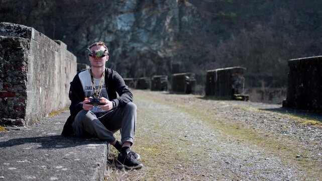 Man flying drone with goggles in mountain setting, feeling focused