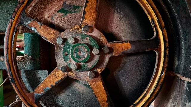 Grungy metal bandsaw flywheel without cover in carpentry workshop