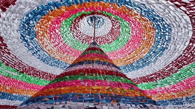 Conical display of vibrant Tibetan prayer flags for tourists and religious purposes.