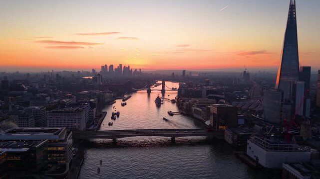 Establishing aerial view of the London skyline with Tower Bridge and River Thames during a colorful sunrise