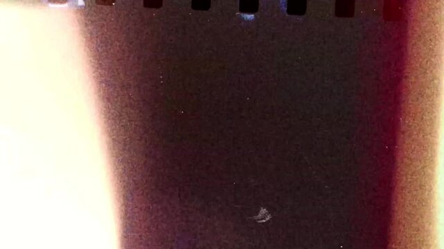 Old film reel transition video animation with dust scratches and sprocket holes effect on black background.