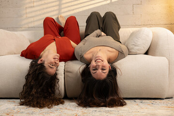 Two women lying upside down on couch laughing © veronica
