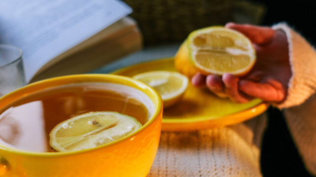Warm cup of tea with lemon slices and an open book on a cozy afternoon