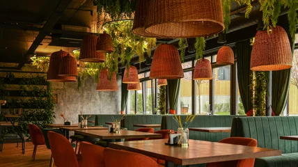 Fotobehang Horeca Modern restaurant interior with hanging rattan lamps and lush greenery  © shine.graphics