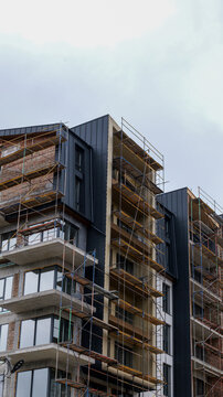 Modern building under construction with scaffolding against a cloudy sky