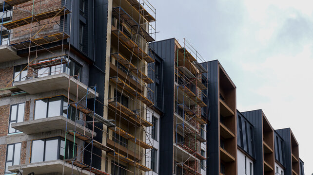 Modern apartment building under construction with scaffolding and balconies