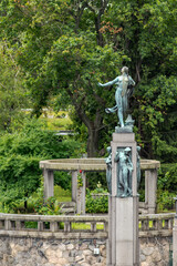 Fototapeta premium Bronze statue fountain in lush green park