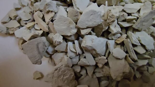 High-quality close-up shot of raw bentonite clay rocks, traditional skincare mineral powder, organic earth material used in spa and beauty treatments, top view, natural texture.