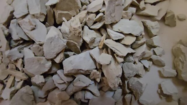 High-quality close-up shot of raw bentonite clay rocks, traditional skincare mineral powder, organic earth material used in spa and beauty treatments, top view, natural texture.