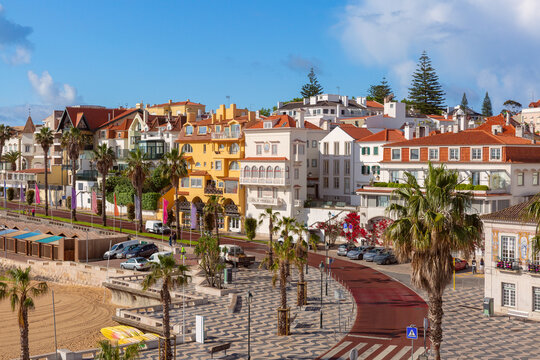 Colorful residential buildings and palm lined waterfront promenade in Cascais, Portugal.