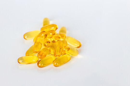 Pile of yellow omega 3 fish oil capsules on white background with copy space. Nutritional supplement and healthcare concept for wellness and healthy lifestyle.