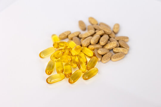 Omega 3 fish oil capsules and vitamin supplement tablets on white background. Healthcare and nutritional supplement concept for wellness and healthy lifestyle.