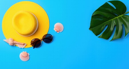 Plakat summer blue banner with yellow hat ,sunglasses,seashell and monstera leaf on blue background top view. 