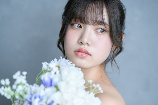 グレー背景でブーケを持って見つめる日本人女性